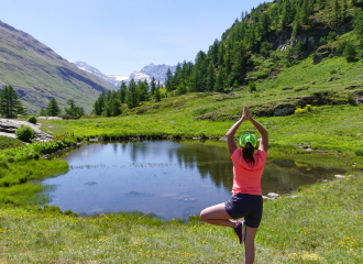 Femme en position de yoga devant un lac d'altitude